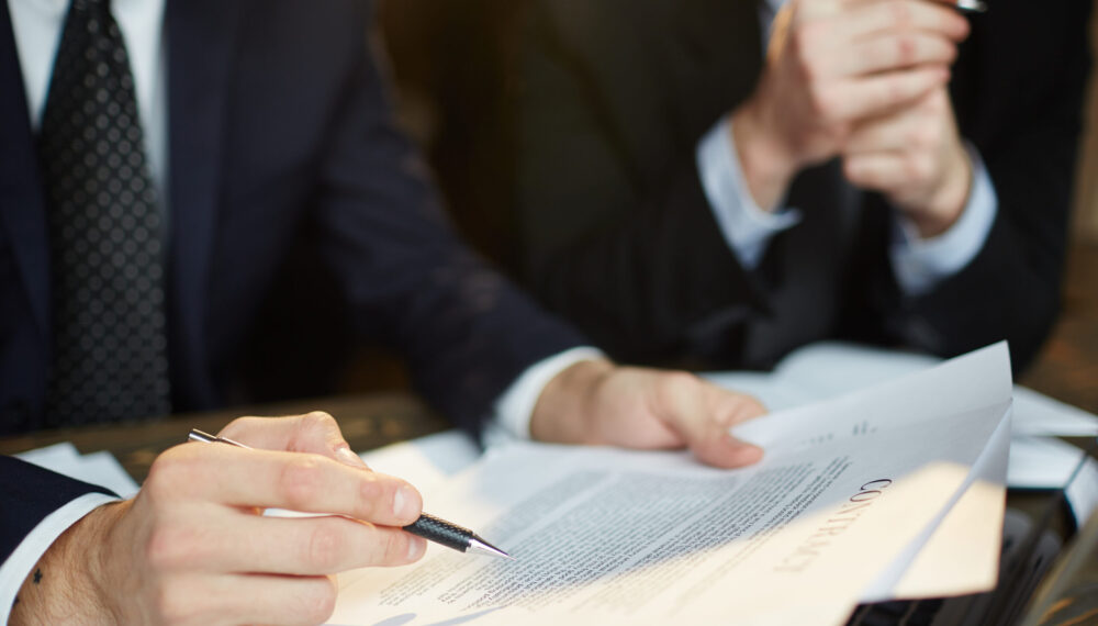 Closeup shot of unrecognizable businessman reading contract documentation at meeting with financial partner